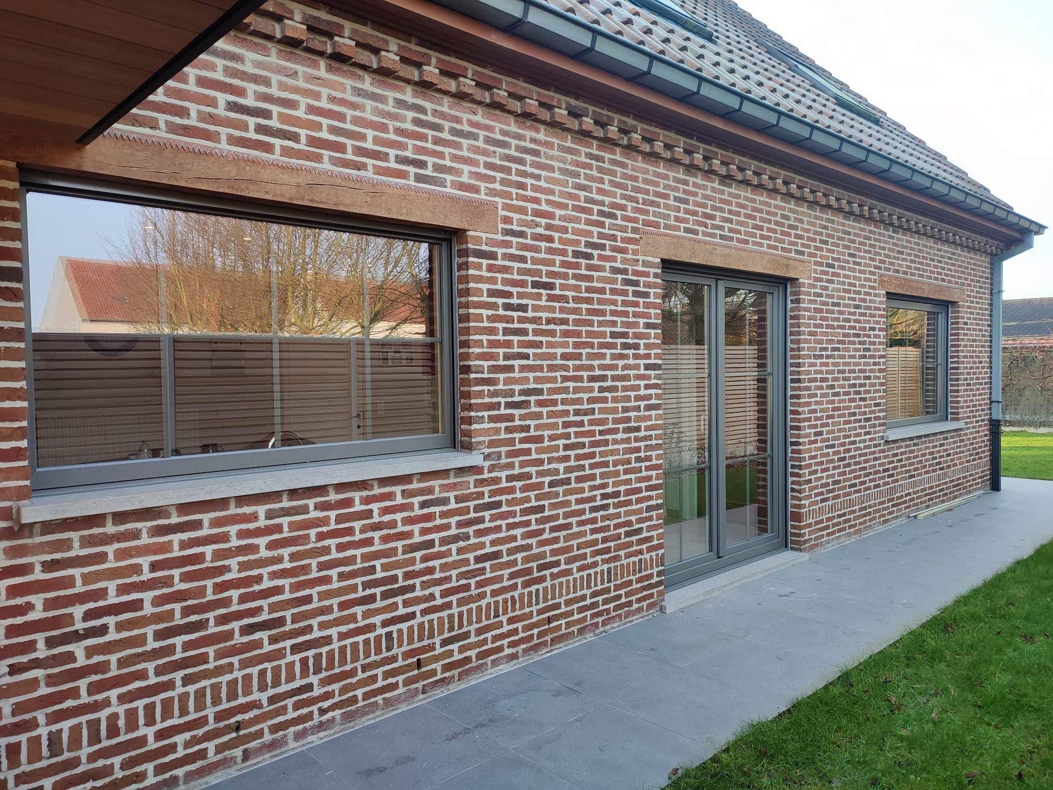 Bakstenen woning met grijze ramen geplaatst door Thimaco